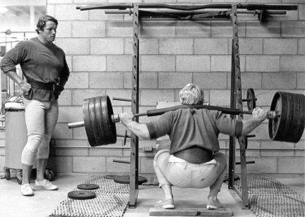 Dave Draper instructs Arnold Schwarzenegger on squatting.