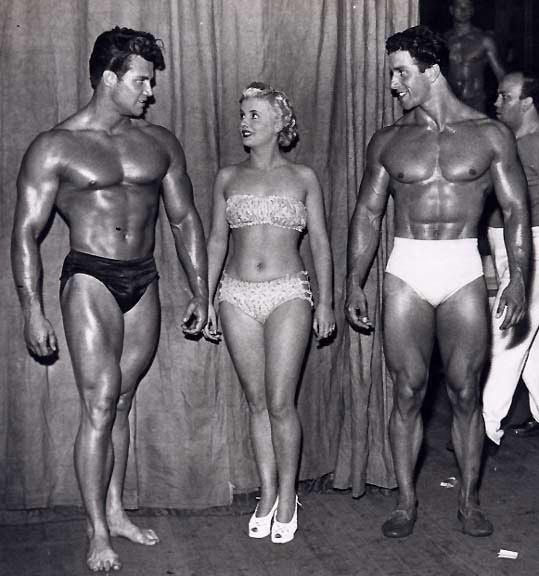 Steve Reeves chats with supermodel as Reg Park looks on.